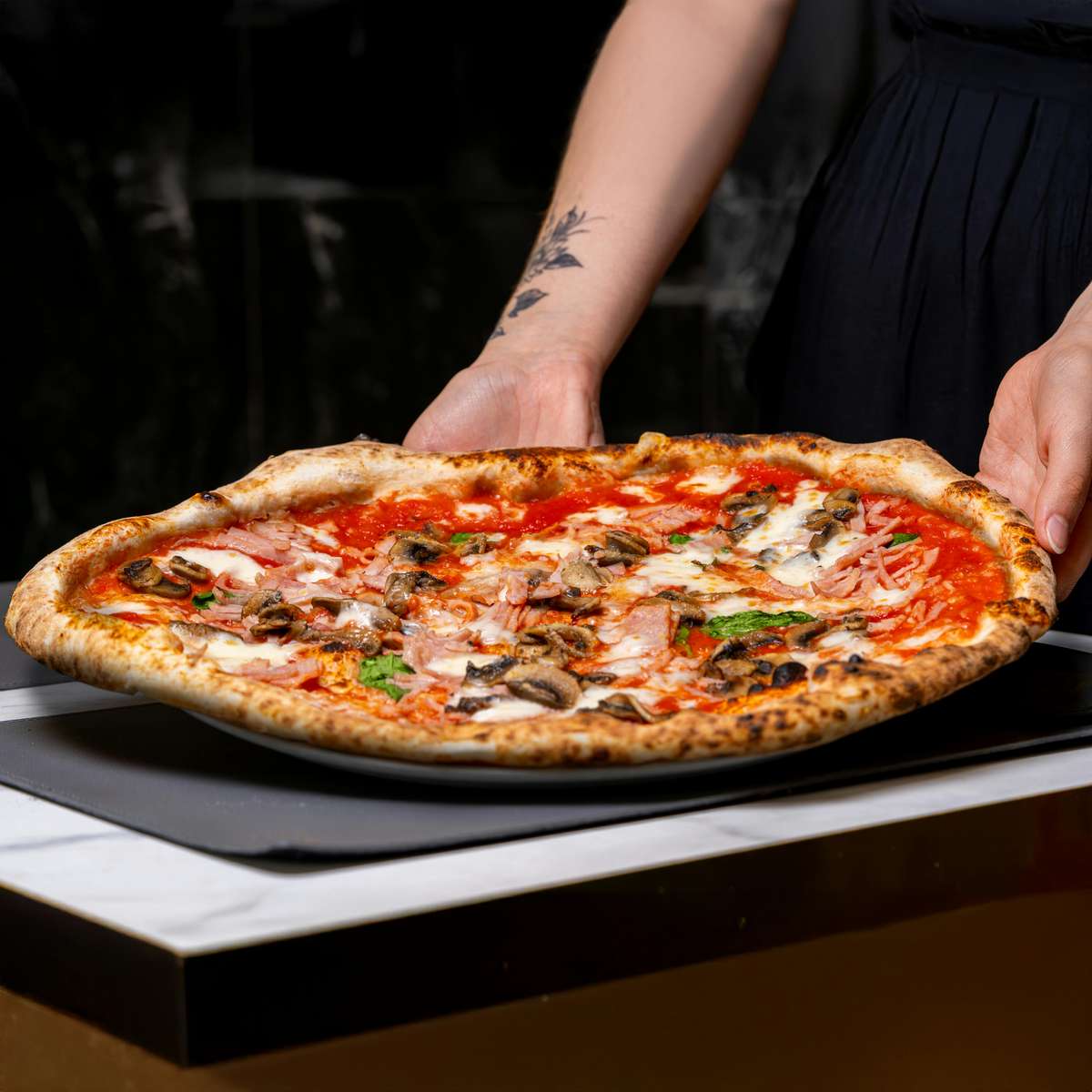 Fresh pizza with toppings being laid down on table