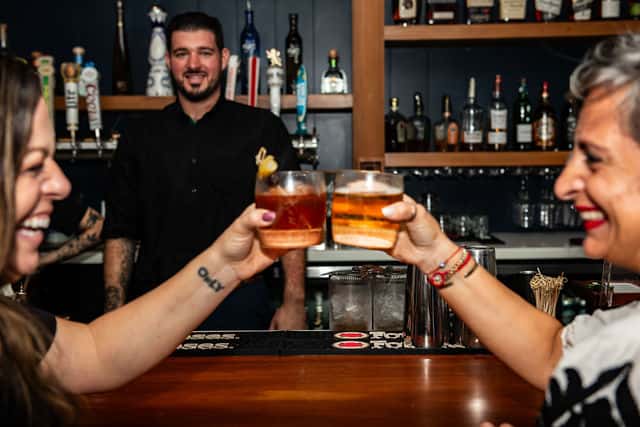 Guests smiling and raising a toast with a bartender at Fin & Tonic in Sarasota.