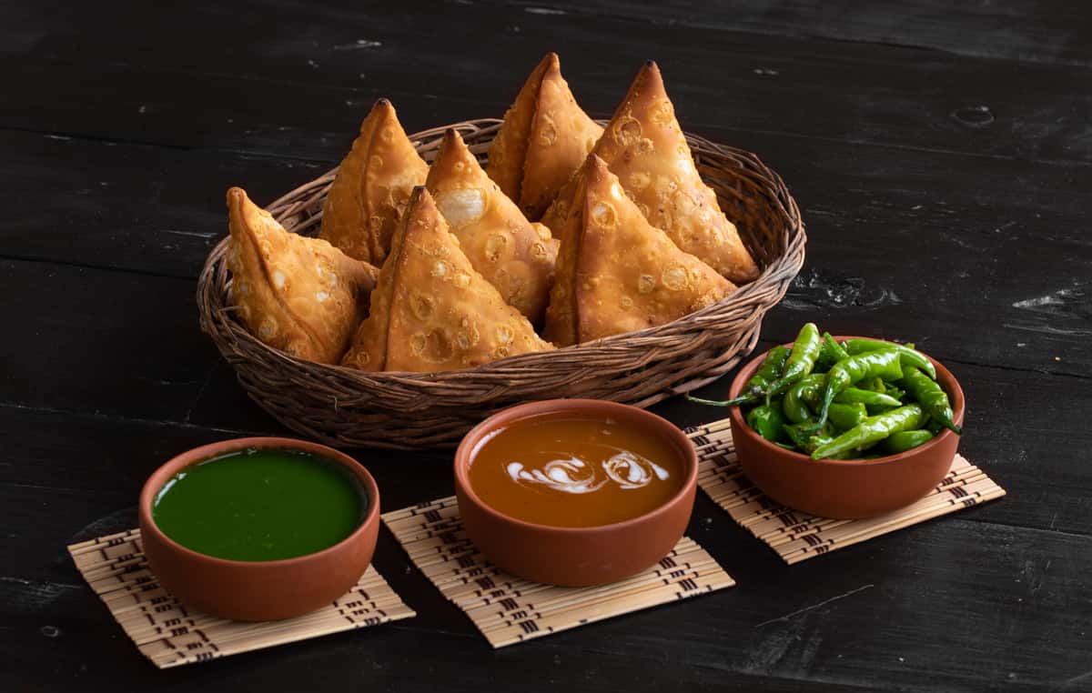 basket of samosa with condiments