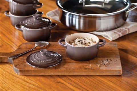 Assorted cookware on table with food in bowl on cutting board.
