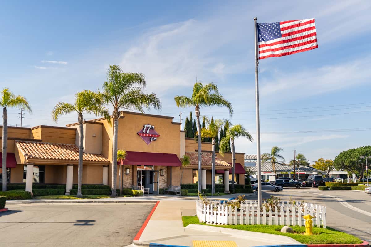 Exterior of The 17th Street Grill surrounded by vibrant green palm trees with a light blue sky.