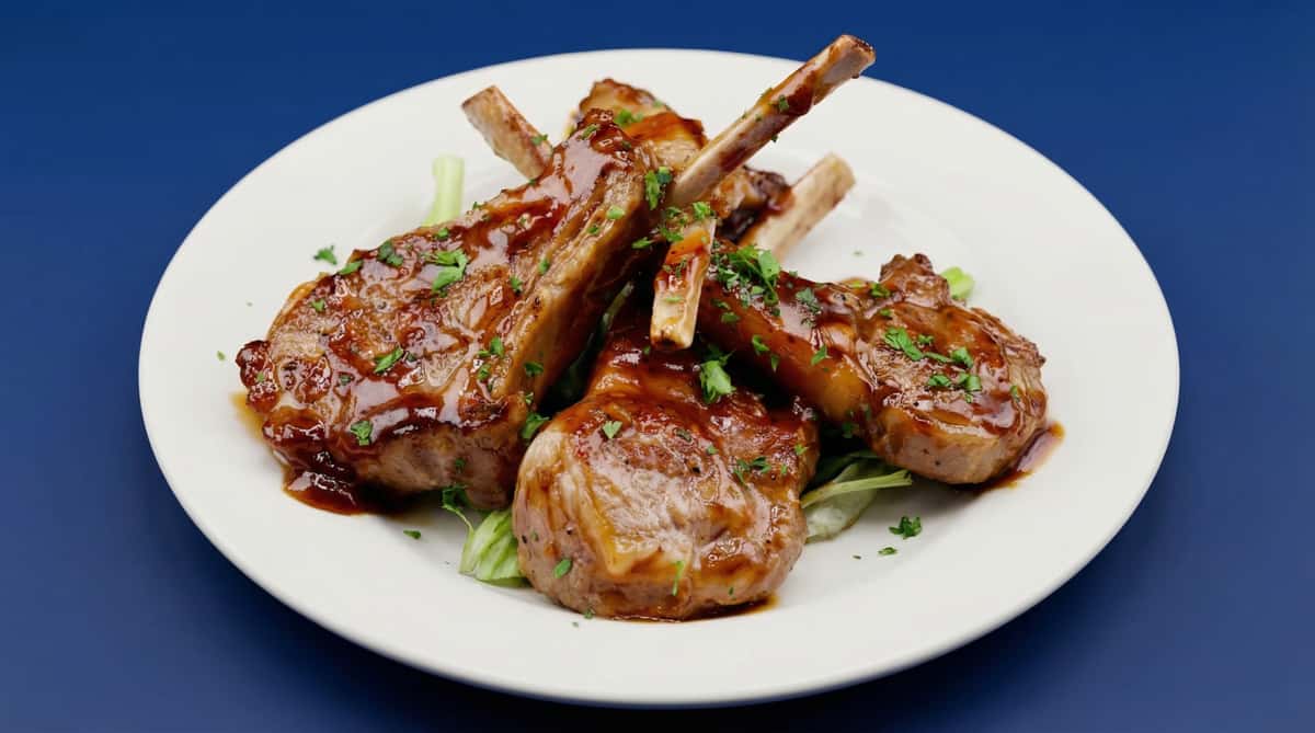 glazed lamb chops with herbs served on white plate, elegant entrée
