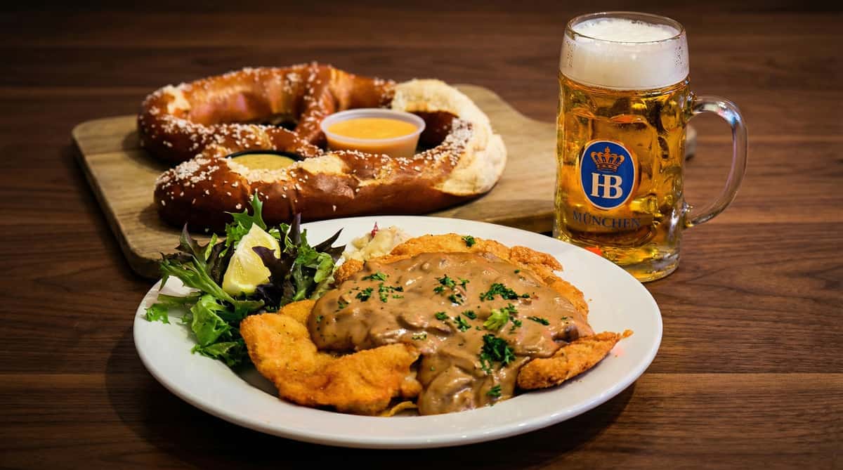 crispy schnitzel with mushroom gravy served with pretzel and German beer