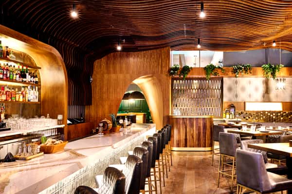 An inviting bar at Fitoor with a warm wooden design, featuring a variety of drinks on display, surrounded by comfortable seating, creating a cozy atmosphere for private events.