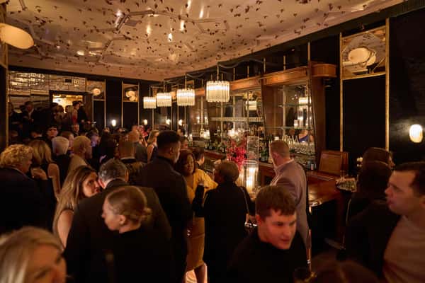 A lively private event at Fitoor, featuring a bustling crowd enjoying drinks and conversation, with elegant decor and a stylish bar in the background.