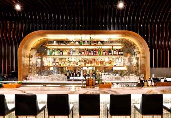 A stylish bar area at Fitoor showcasing a wide selection of spirits on illuminated shelves, with modern seating and a sleek design, ideal for socializing during private events.