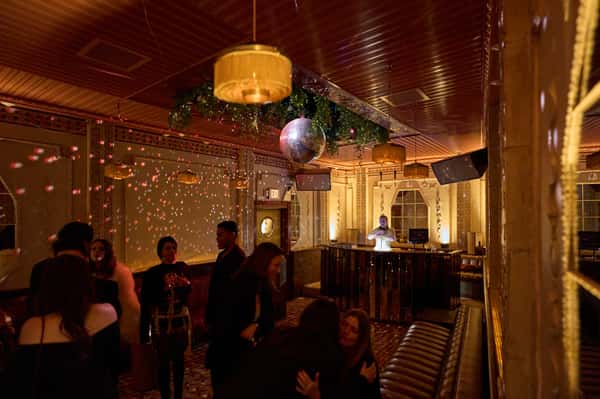 An elegant private event space with a dramatic black ceiling and chandeliers, filled with guests enjoying a sophisticated gathering at Fitoor.