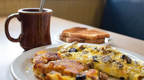 Golden omelet filled with vegetables and cheese, served with toasted bread and a hot cup of coffee.