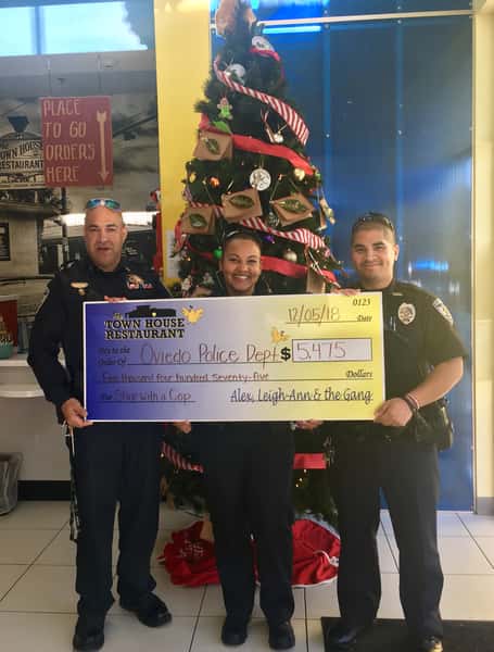 three police officers holding a check to the Oviedo Police Department
