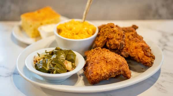 Crispy fried chicken served with macaroni and cheese, seasoned greens, and golden cornbread.