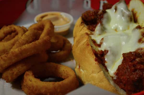 Meatball parmesan sub with a side of onion rings.