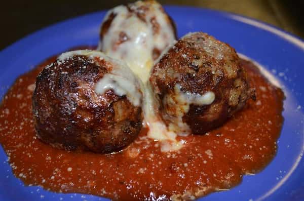 Three meatballs in marinara sauce and melted mozzarella cheese.