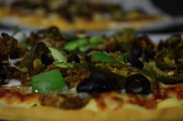 Closeup of pizza with olives, jalapenos and green peppers.