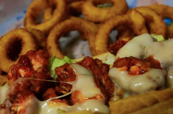 Crispy Buffalo Chicken. Crispy chicken breast tossed in wing sauce with lettuce, tomatoes, mayo and Swiss cheese. Served with a side of onion rings.