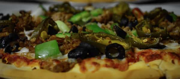 Closeup of pizza with olives, jalapenos and green peppers.