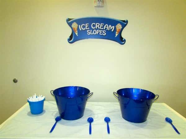 two large buckets with spoon and a sign that reads ice cream slopes