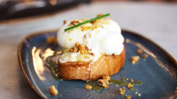 Brie Tantan brunch dish at Bossa Nova Brazilian Cuisine featuring toasted sourdough topped with melted brie, creamy burrata, cupuaçu jam, caramelized walnuts, and a drizzle of honey on a blue plate.