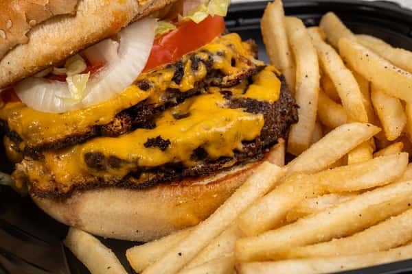 Close-up of a double meat cheeseburger with melted cheese served with french fries.