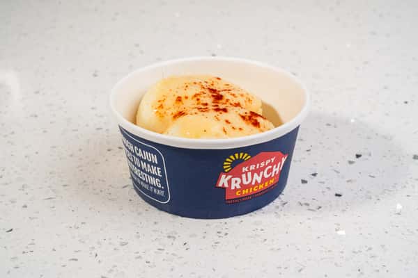 Cup of mashed potatoes topped with gravy and seasoning.
