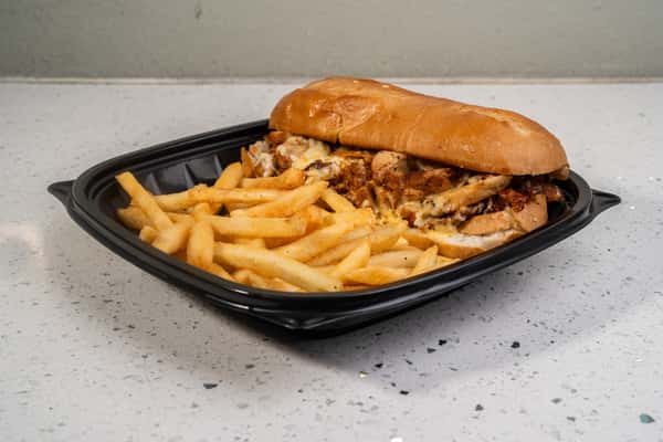 Chicken Philly cheesesteak sandwich served with french fries.