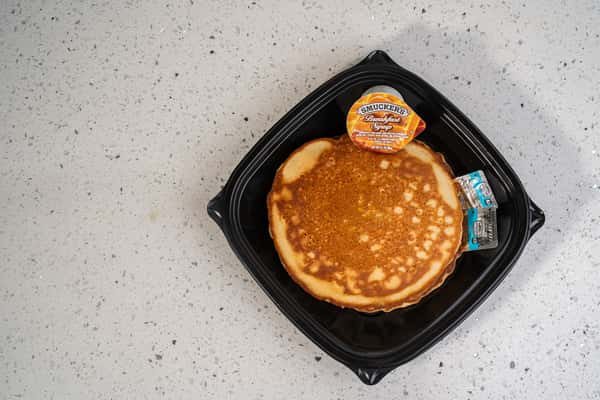 Stack of sweet cream pancakes served in a black takeout container.