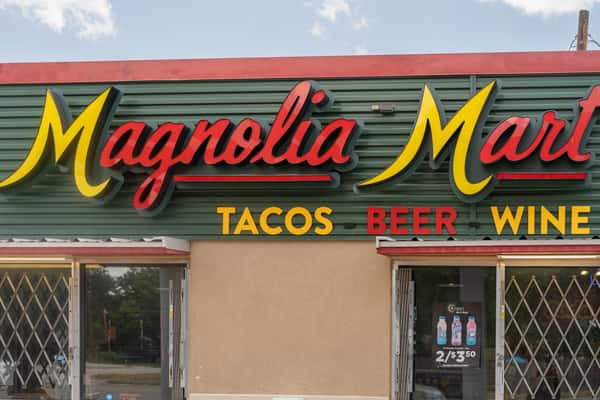 Close-up of the Magnolia Mart storefront sign reading tacos, beer, and wine.