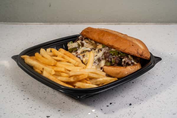 Philly cheesesteak sandwich served with french fries in a black takeout tray.