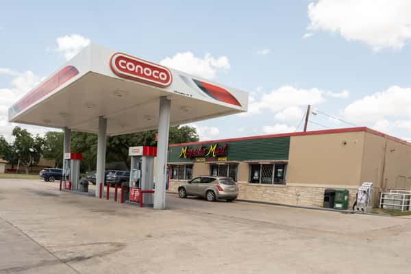 Wide exterior view of the Magnolia Mart and Conoco gas station under a blue sky.