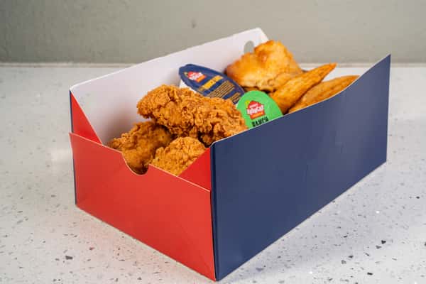 Chicken tender meal with fries and dipping sauces in a red and blue takeout box.