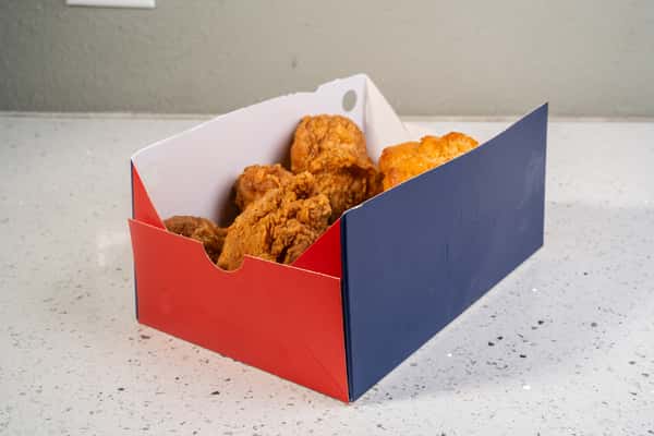 Fried chicken and biscuit meal served in a red and blue takeout box.