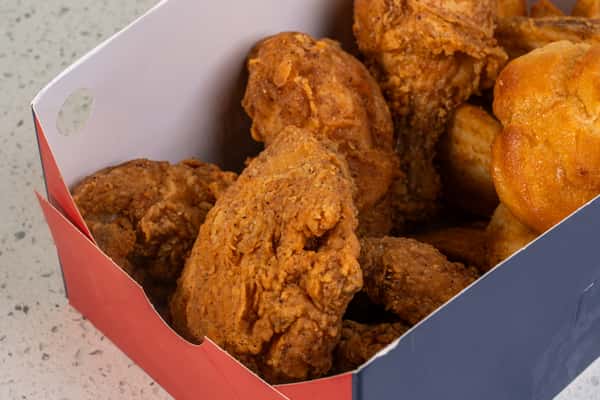 Close-up of crispy fried chicken and biscuits served in a takeout box.