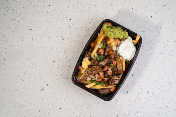 Beef fajita asada fries topped with grilled meat, vegetables, guacamole, and sour cream.