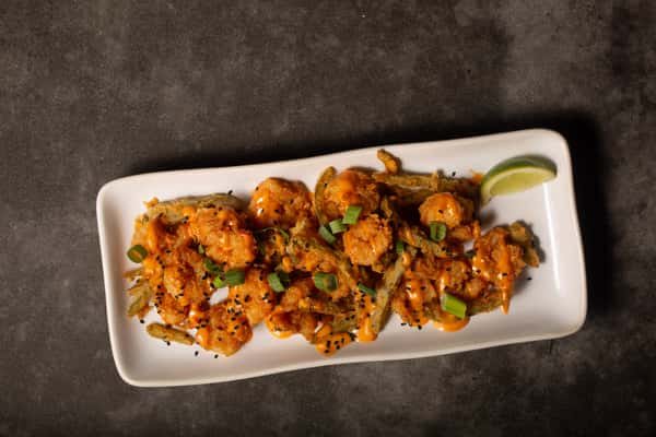 Crispy bang bang shrimp appetizer tossed in spicy sauce and topped with green onions and sesame seeds