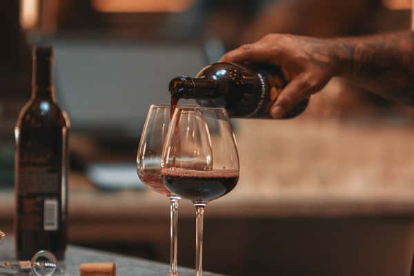 person pouring red wine