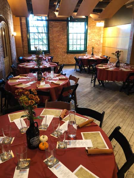 Orange table clothes with growlers filled with flowers for an autumn event