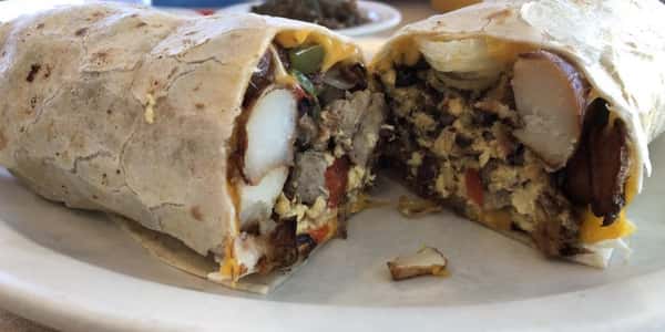A breakfast burrito with eggs, tomato, beans, and bacon