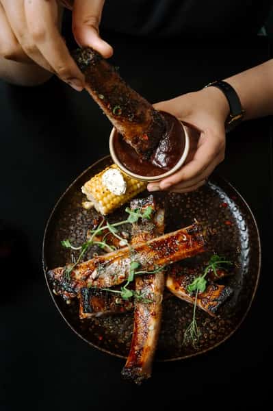 grilled barbecue ribs being brushed with sauce in a close-up kitchen preparation shot