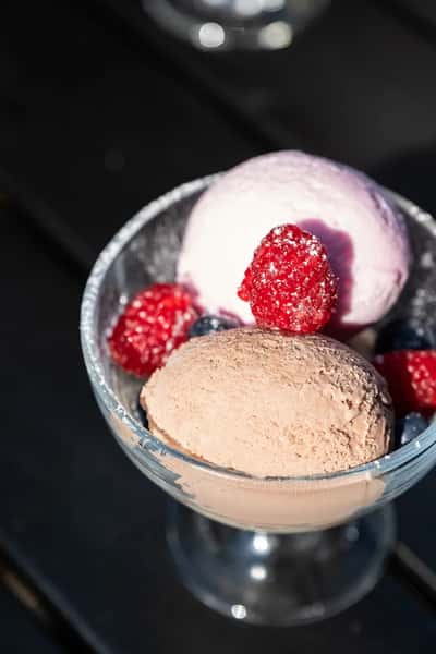 scoops of ice cream topped with fresh raspberries and chocolate crumble dessert