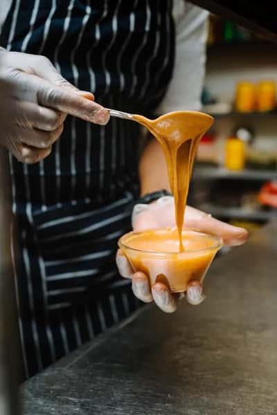 creamy cheese sauce being poured from a spoon in a close-up food preparation shot