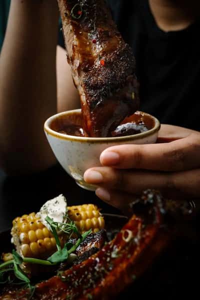 crispy chicken wing dipped into sauce in a close-up restaurant food shot