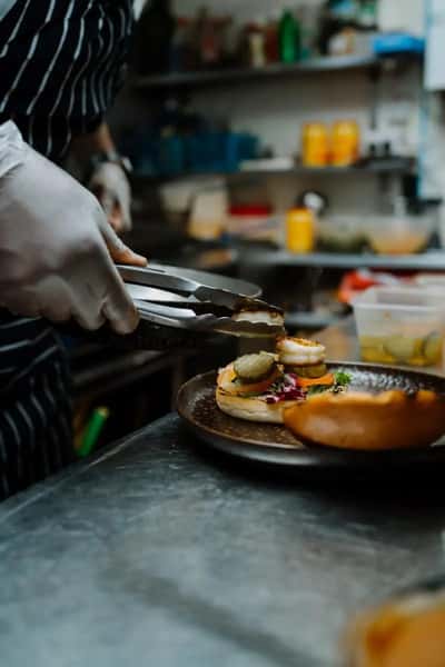 chef plating a gourmet burger in a professional kitchen with careful presentation