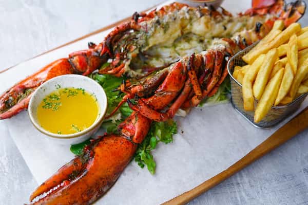fresh lobster tail plated with butter sauce and herbs in an upscale seafood presentation