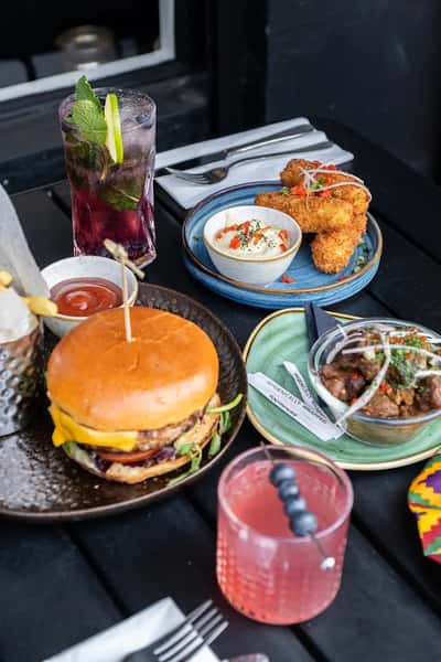gourmet cheeseburger with fries and dipping sauces on a table with small plates in a trendy restaurant