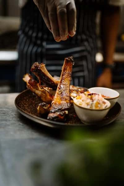 barbecue ribs glazed in sauce served with a side of coleslaw on a rustic plate in a casual restaurant setting