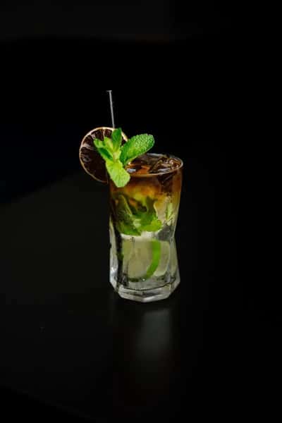mojito cocktail with fresh mint and lime in a tall glass against a dark background