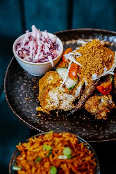 crispy fried chicken plate with seasoned sides and pickled onions in a modern casual restaurant
