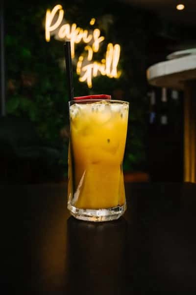 Refreshing tropical cocktail with ice and fruit garnish served in a tall glass at a stylish restaurant bar