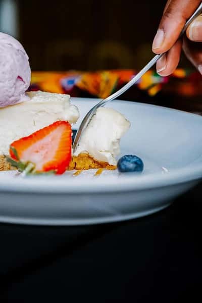 Elegant plated dessert with fresh strawberries, blueberries, and a scoop of creamy ice cream in a fine dining setting