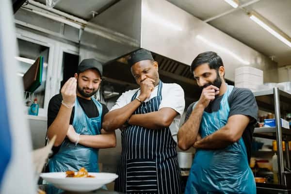 restaurant kitchen staff posing together in uniforms inside a busy commercial kitchen