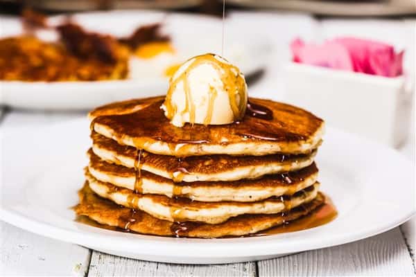 Stacked pancakes with syrup and a dallop of butter on top